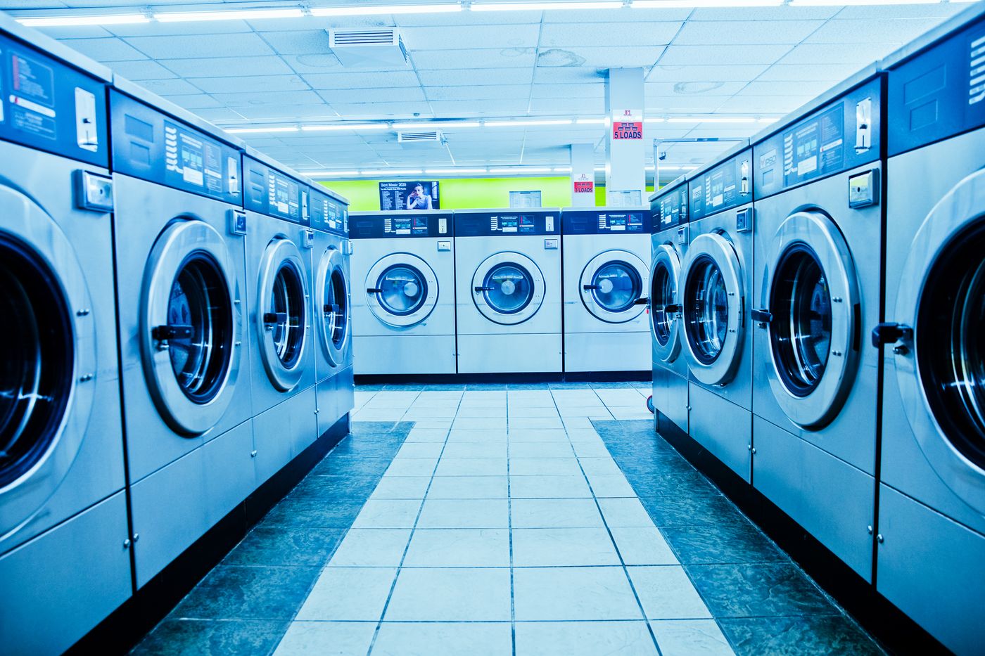 Rows of clean front-load washing machines in a bright laundromat