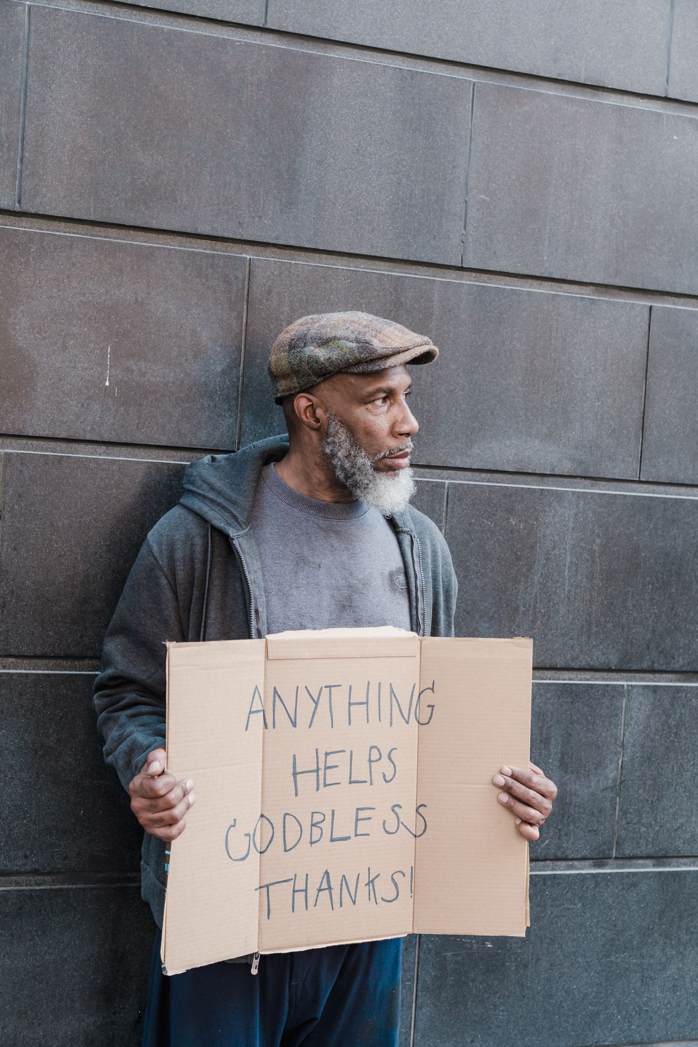 A man holding a cardboard sign that reads Anything Helps